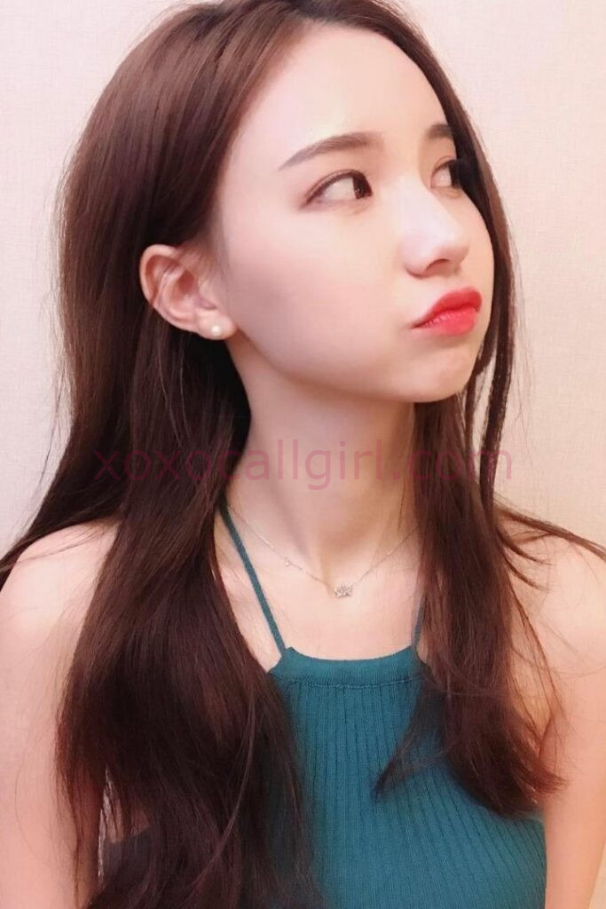 KL Escort Girl Fiona, a Chinese Escort KL Outcall, poses with red lipstick and a green top. Malaysia Sex Service