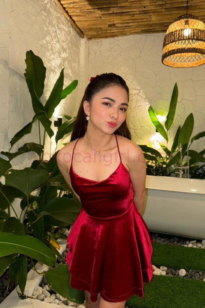 KL Escort Girl Malay Escort in Kuala Lumpur wearing a red dress, surrounded by plants. Malaysia Sex Service