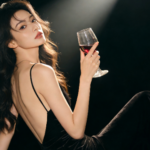 Elegant woman in black dress holding red wine glass.